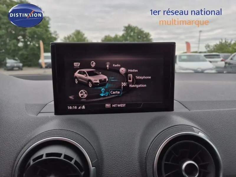 Écran central de l'Audi Q2 1.4 TFSI gris Manhattan montrant le menu multimédia et navigation, vue intérieure avant.