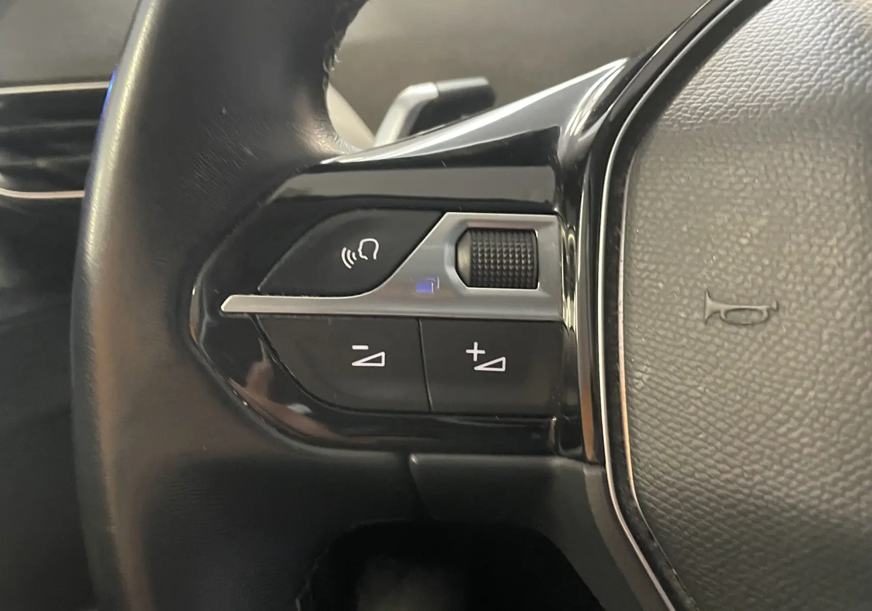 Gros plan sur les commandes de volume au volant noir du Peugeot 5008 blanc nacré, version 1.5 BlueHDi 130 Allure EAT8 de 2019.