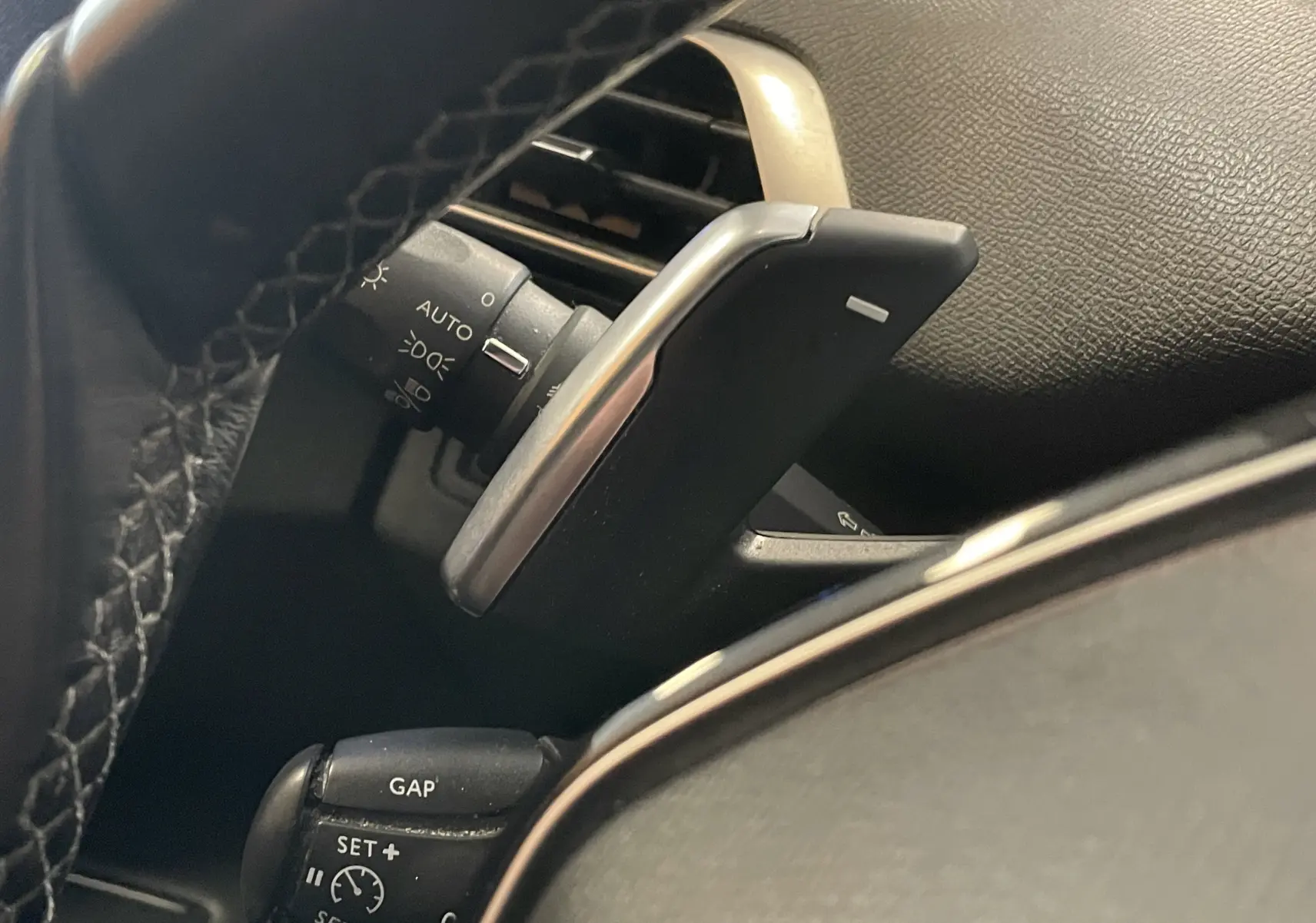 Le levier de commande de régulateur de vitesse et la palette de changement de vitesses sur le volant d'un Peugeot 5008 blanc nacré.