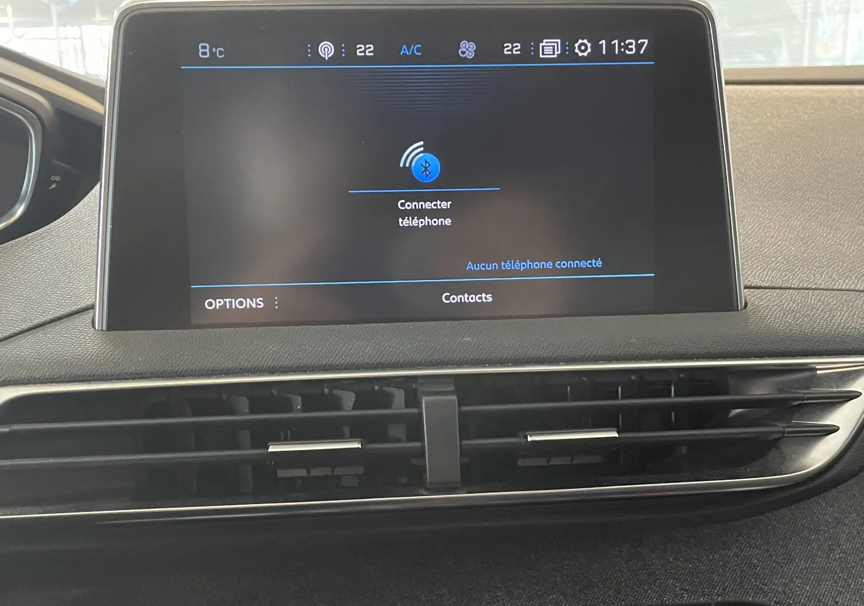Écran tactile central du tableau de bord du Peugeot 5008 blanc nacré, affichant la connexion Bluetooth et la climatisation.