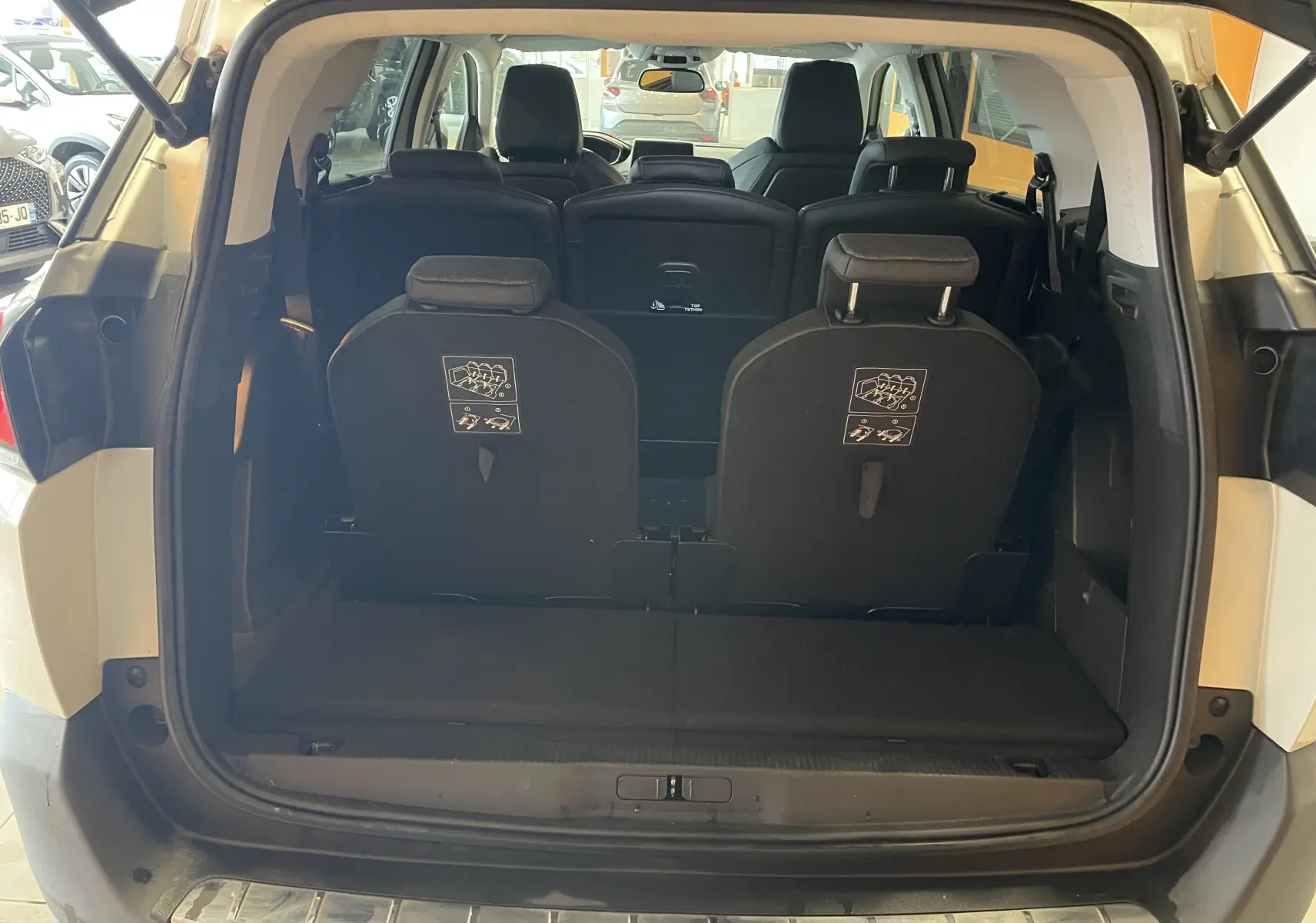 Vue arrière ouverte du Peugeot 5008 blanc nacré, montrant les sièges arrière et le coffre spacieux.