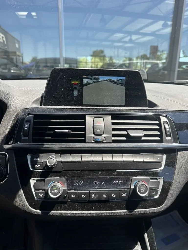 Vue rapprochée de la console centrale d'une BMW Série 1 F20 gris foncé, avec écran multimédia affichant la caméra de recul.