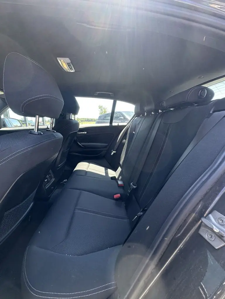 Vue intérieure arrière de la BMW Série 1 F20 116D 2019, sièges arrière en tissu noir avec surpiqûres blanches.