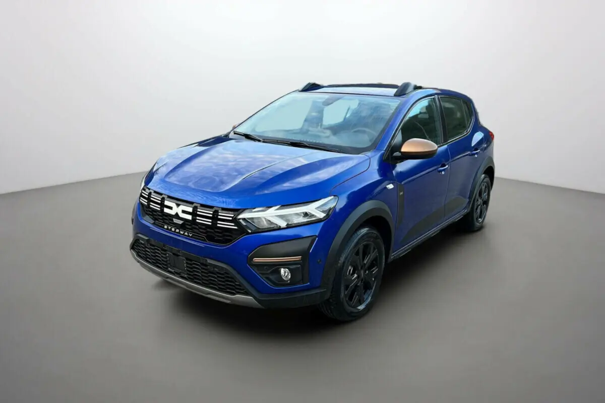 Dacia Sandero Stepway 2024 bleu iron en 3/4 avant droit avec coques de rétroviseurs bronze et jantes noires.