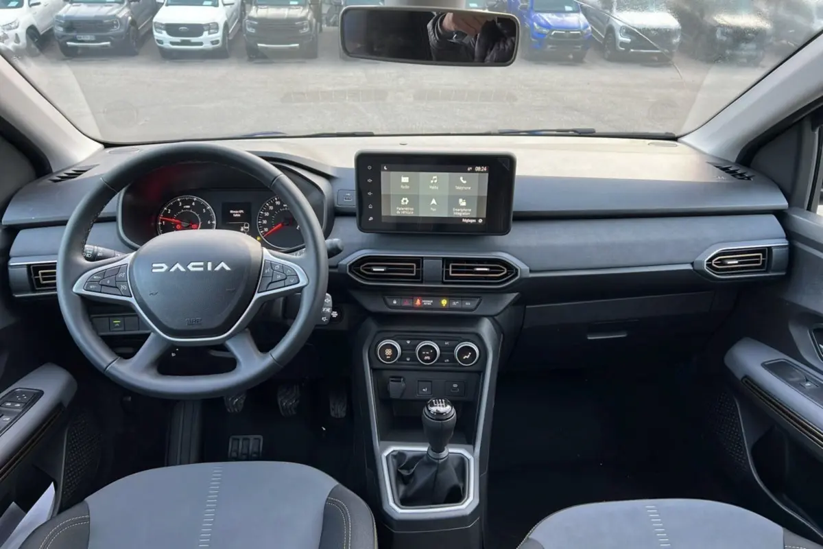 Vue intérieure avant du tableau de bord et volant Dacia Sandero Stepway Bleu iron avec boîte manuelle et écran tactile central.