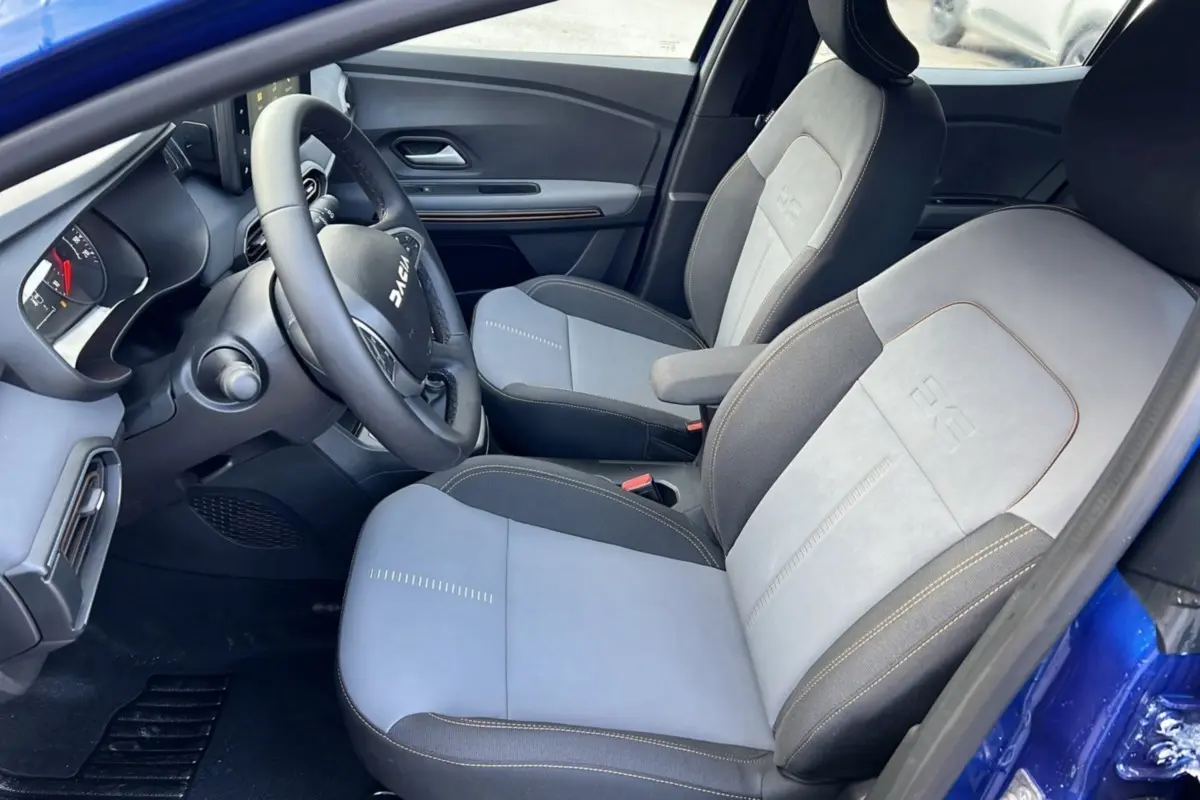 Intérieur de la Dacia Sandero Stepway 2024 en bleu iron, vue côté conducteur montrant sièges bi-ton et volant multifonction.