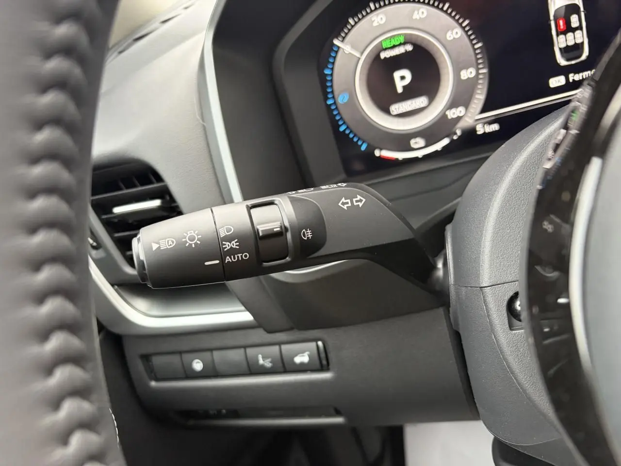 Gros plan sur la manette de clignotants et tableau de bord numérique du Nissan Qashqai 2025, intérieur noir.