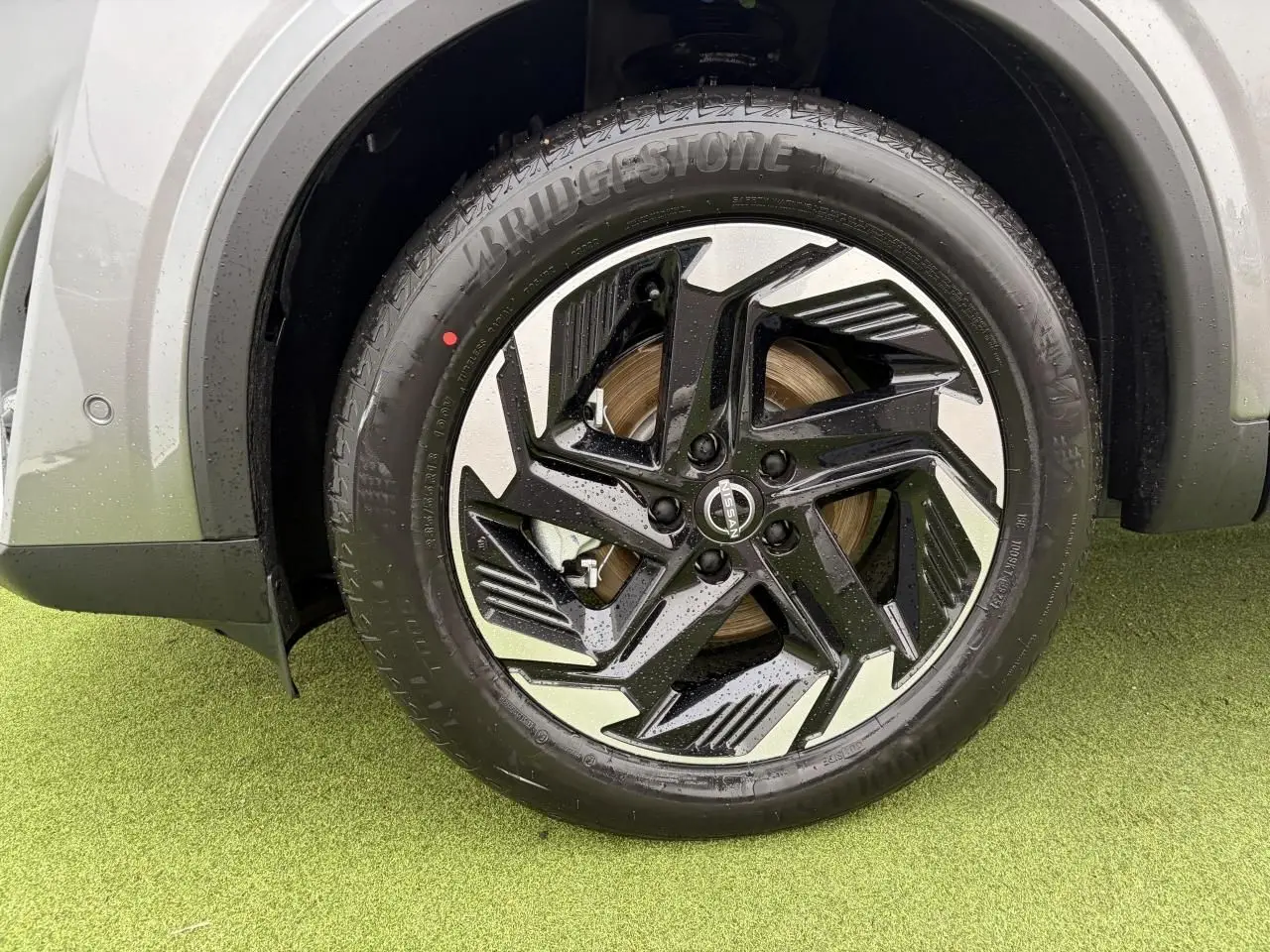 Gros plan sur la roue avant droite du Nissan Qashqai 2025 gris foncé avec jante alliage noire et argentée design moderne.