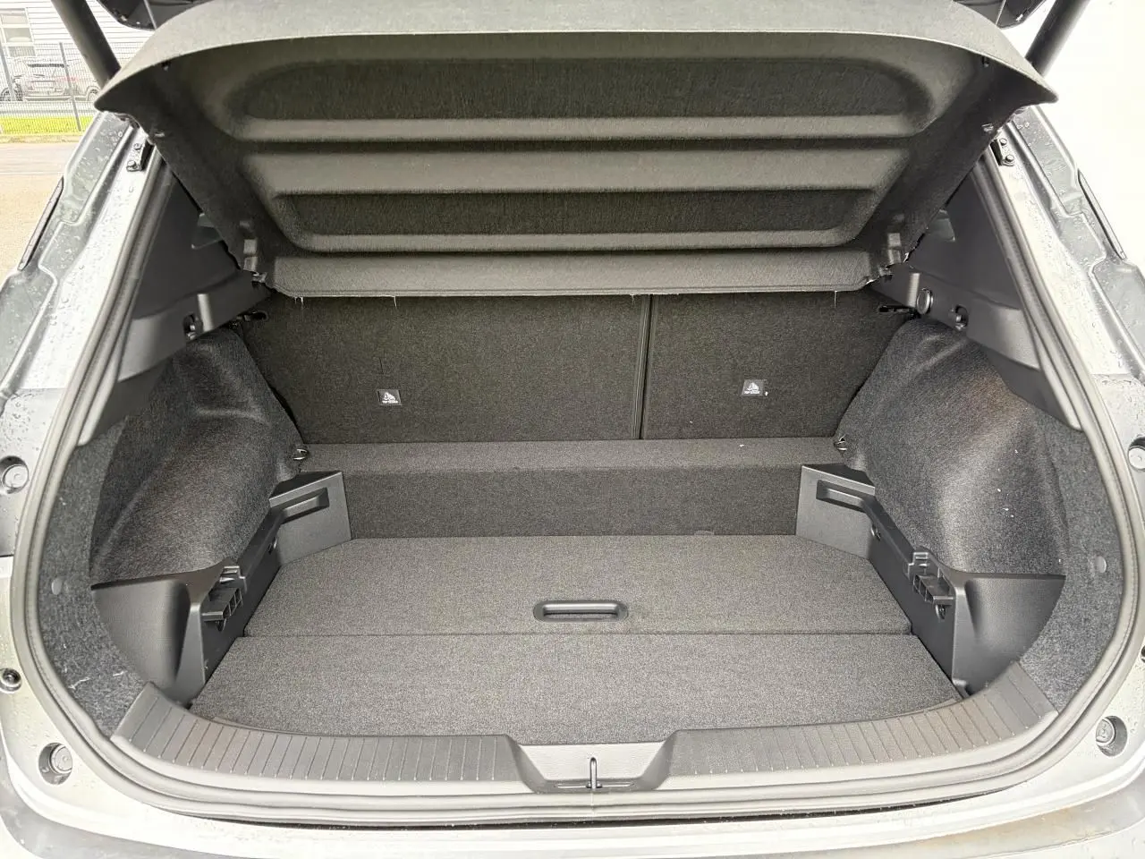 Coffre ouvert vu de l'arrière du Nissan Qashqai III 1.5 Hybrid e-Power gris foncé, espace de chargement vide et propre.