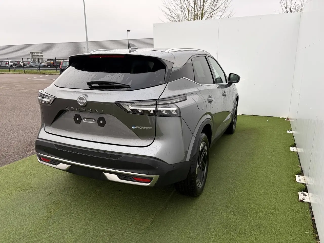 Vue 3/4 arrière droite du Nissan Qashqai III 1.5 Hybrid e-Power gris foncé métallisé avec badges e-POWER visibles.