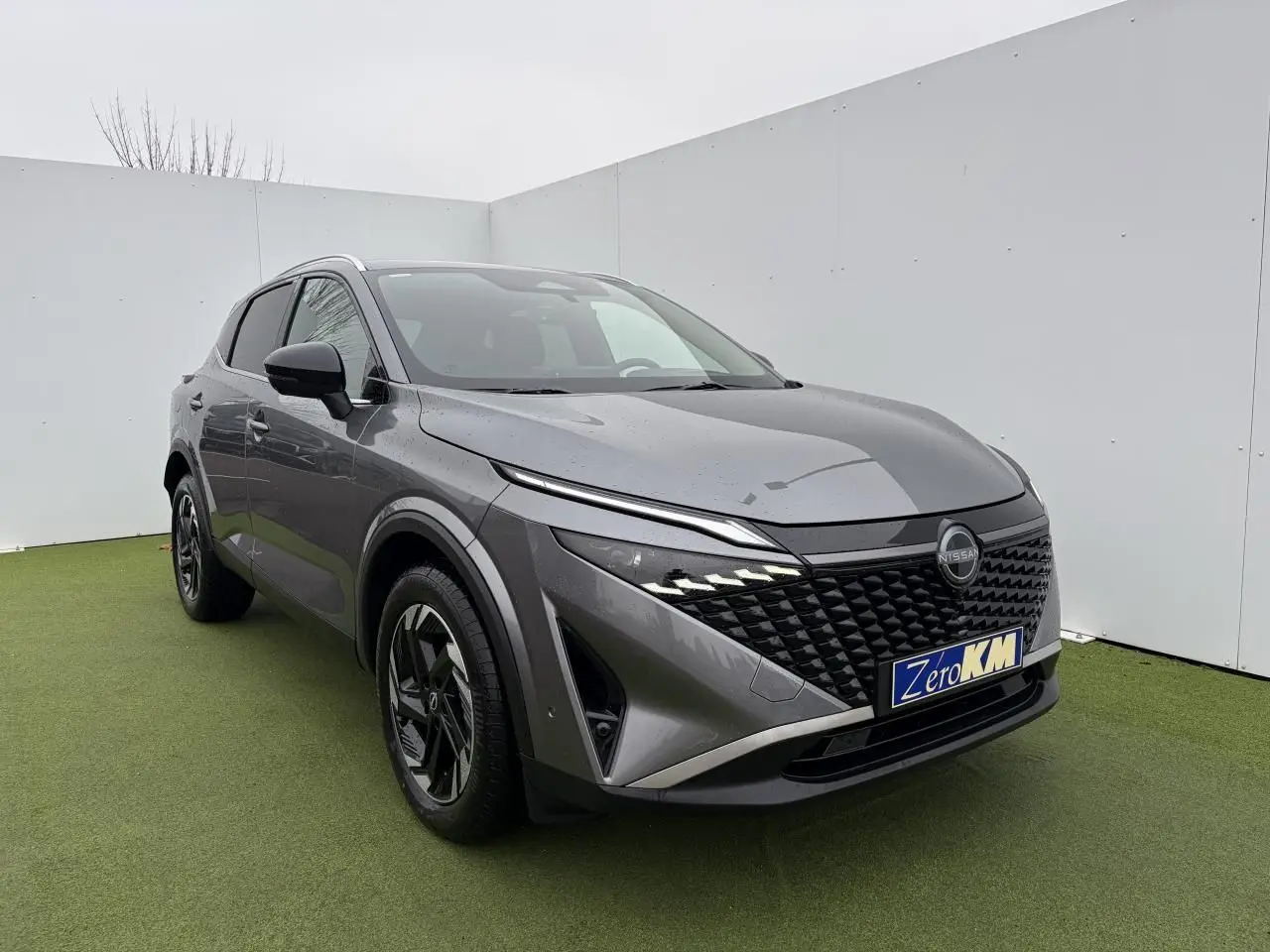 Nissan Qashqai III 1.5 Hybrid e-Power gris foncé métal en 3/4 avant avec calandre noire et jantes alliage.
