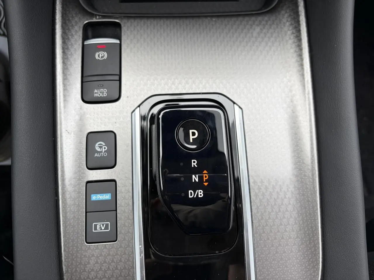 Vue rapprochée de la console centrale grise avec sélecteur de boîte auto et boutons de contrôle du Nissan Qashqai hybride.