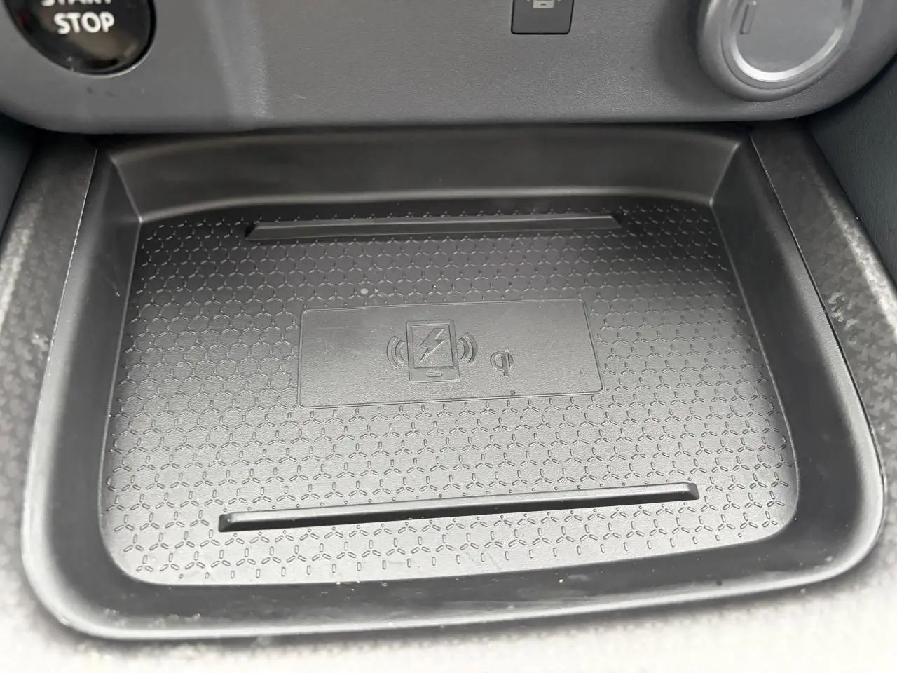 Gros plan sur le chargeur à induction noir dans la console centrale du Nissan Qashqai III gris foncé.