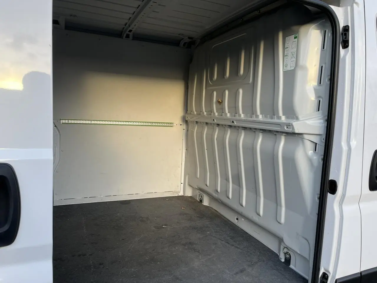Vue intérieure de la zone de chargement du fourgon blanc Opel Movano, côté droit avec plancher et parois métalliques.