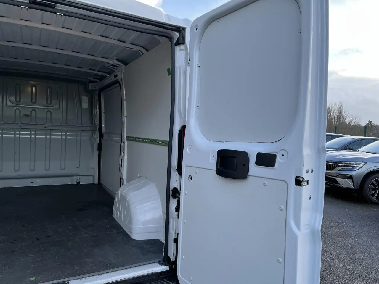Vue arrière ouverte du fourgon blanc Opel Movano 2024, montrant l’intérieur vide et le plancher noir.