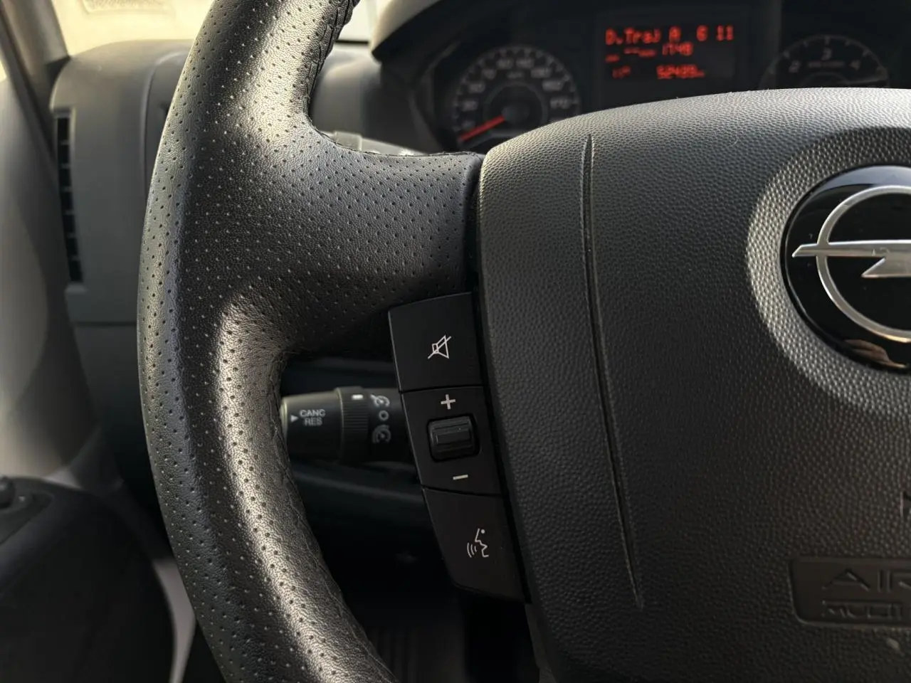 Gros plan sur le volant noir perforé d’un Opel Movano Fourgon 2024 avec commandes audio intégrées.