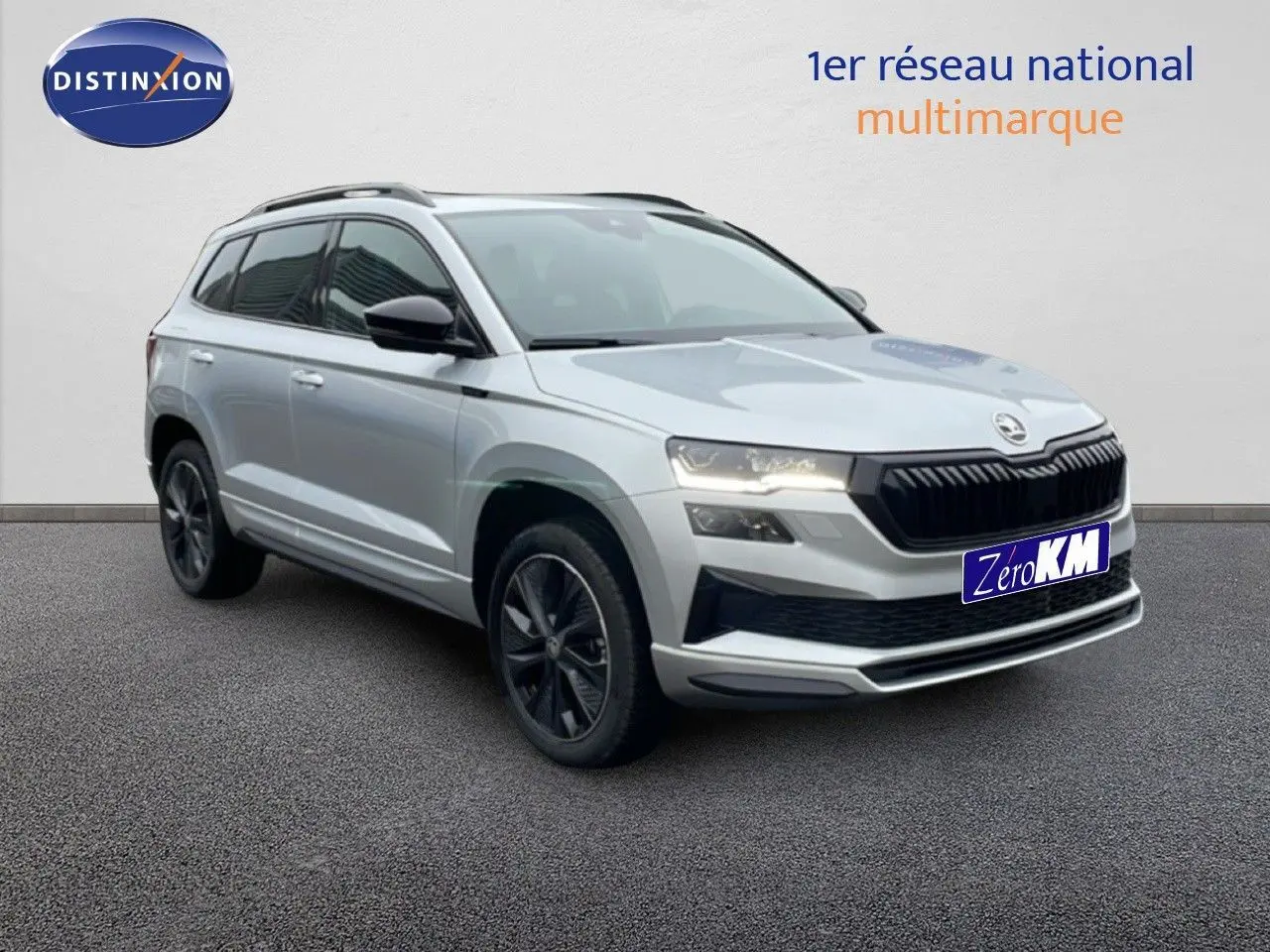 SUV Skoda Karoq gris argent métal en 3/4 avant droit, avec calandre noire et jantes foncées distinctives.