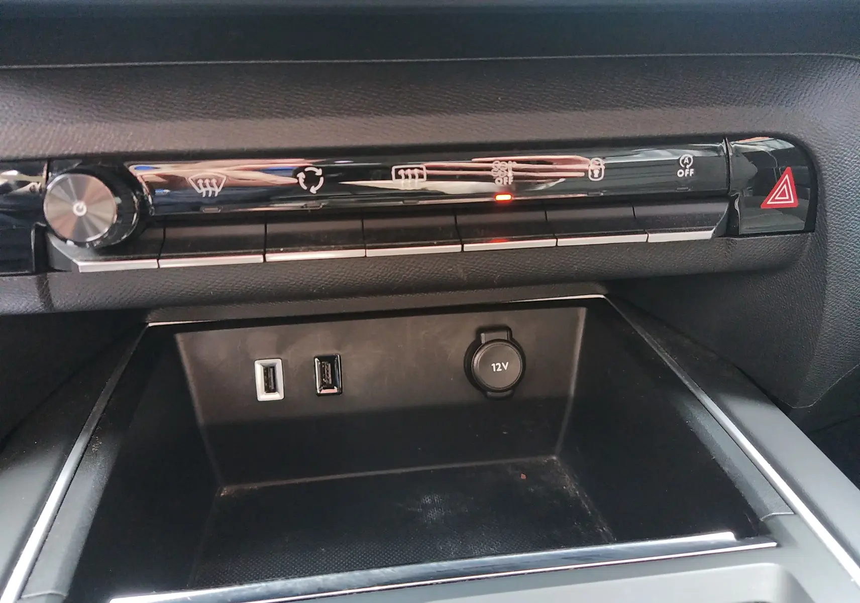 Vue rapprochée de la console centrale noire du Citroën C5 Aircross 2023, avec commandes climatisation et ports USB et 12V.