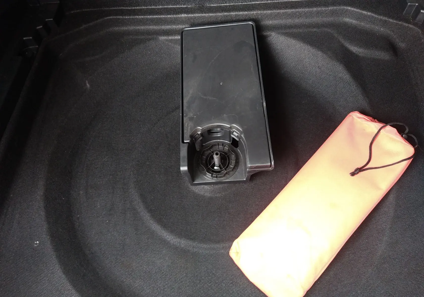 Vue rapprochée du coffre d’un Citroën C5 Aircross 2023 montrant le rangement sous plancher avec un sac orange.