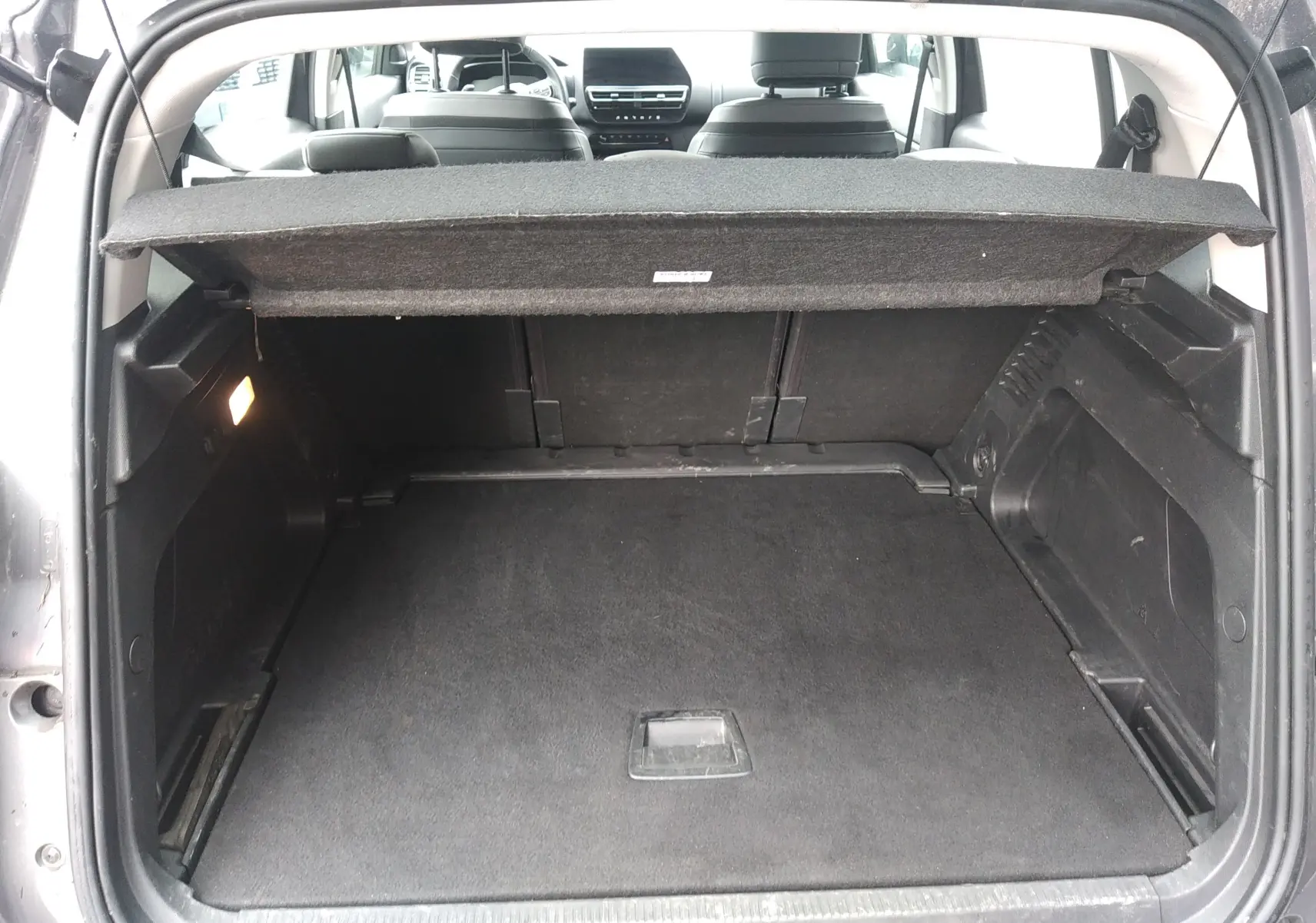 Coffre ouvert vu de l'arrière d'un Citroën C5 Aircross gris, avec cache-bagages et intérieur noir visible.