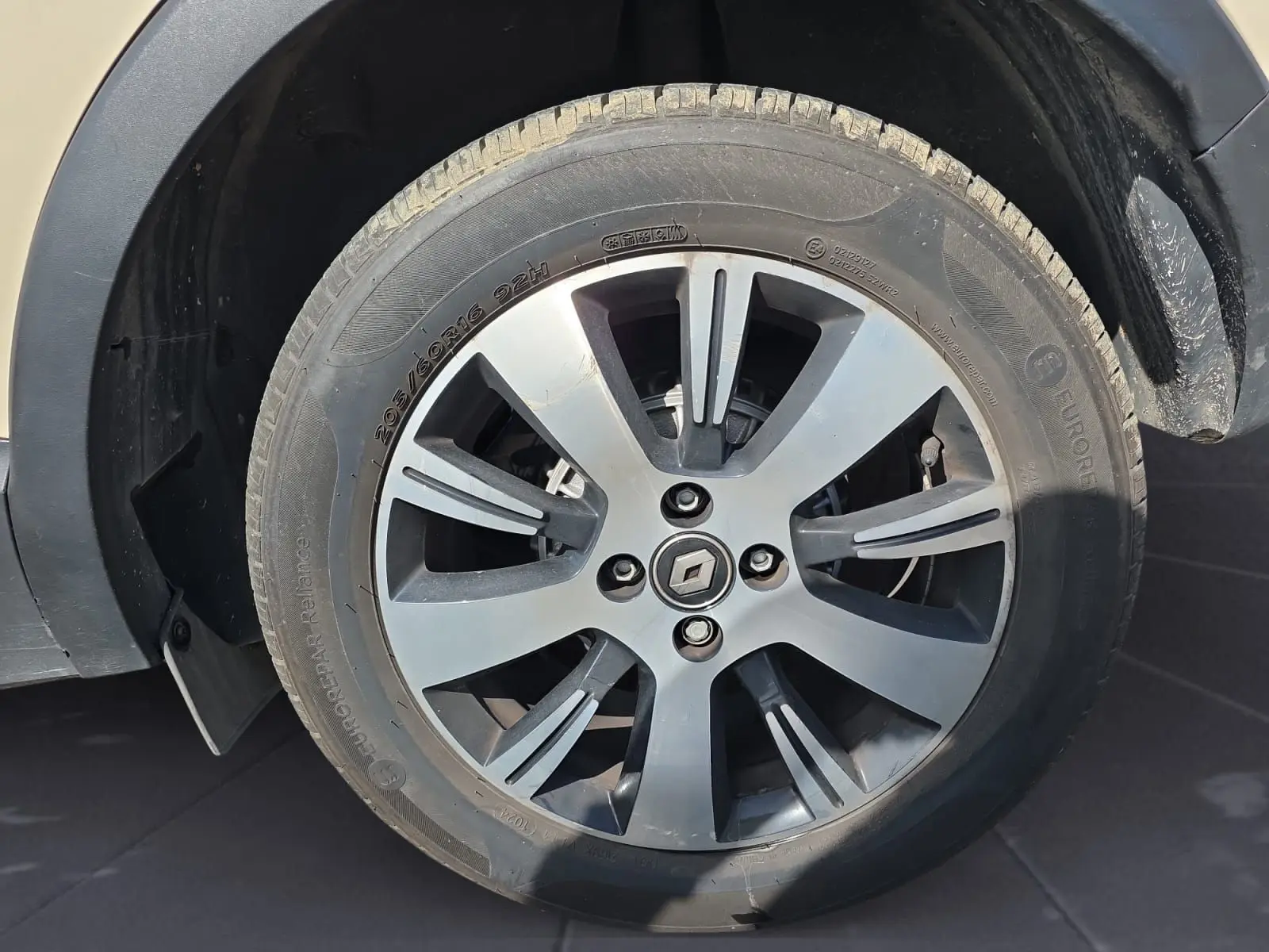 Gros plan sur la roue avant gauche d’un Renault Captur ivoire, mettant en valeur la jante alliage 16 pouces avec logo Renault central.