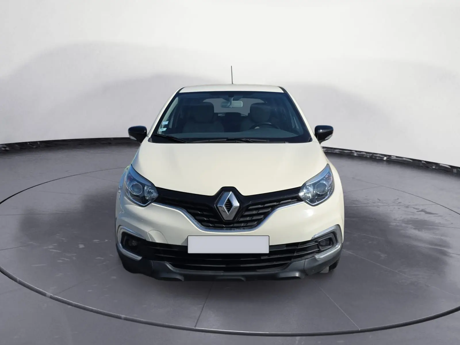 Vue frontale d'un Renault Captur ivoire 2018 avec calandre noire et phares arrondis, sur fond neutre.