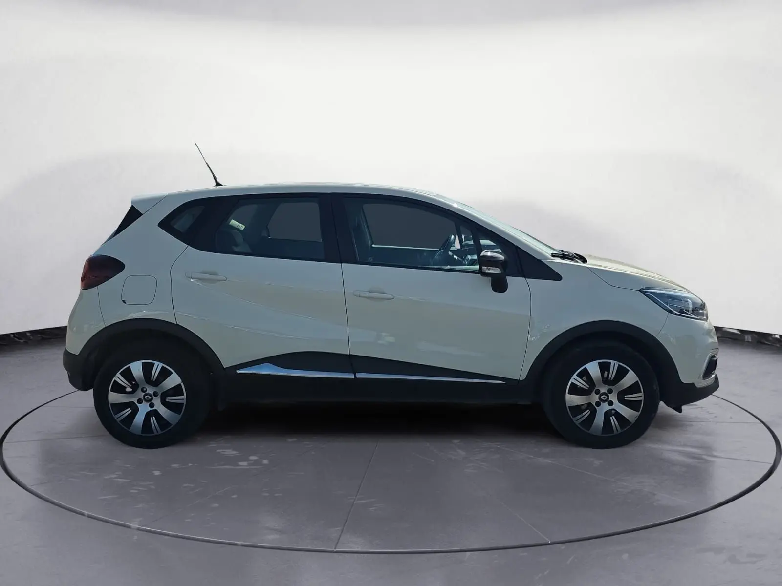 Renault Captur ivoire vue de profil côté gauche, avec jantes alliage et protections noires sur les bas de caisse.