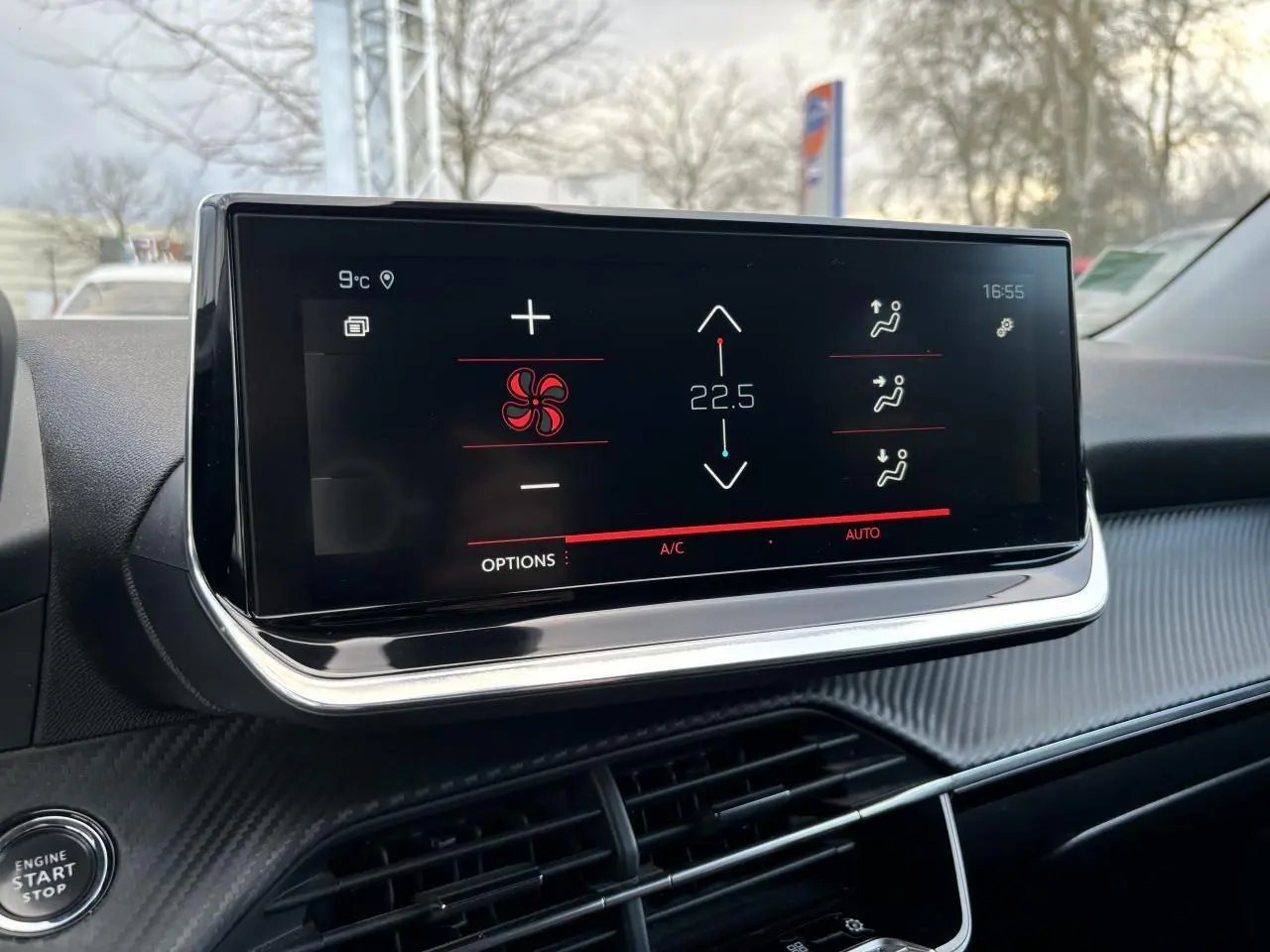 Écran tactile 10 pouces du tableau de bord du Peugeot 2008 affichant la climatisation à 22,5°C en extérieur urbain.