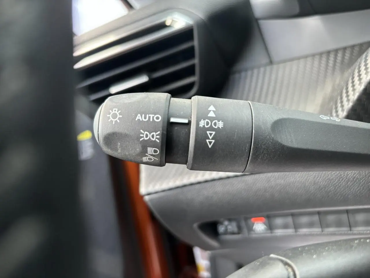 Gros plan sur la commande des phares et clignotants dans l'habitacle d'une Peugeot 2008 Orange Fusion 2021.