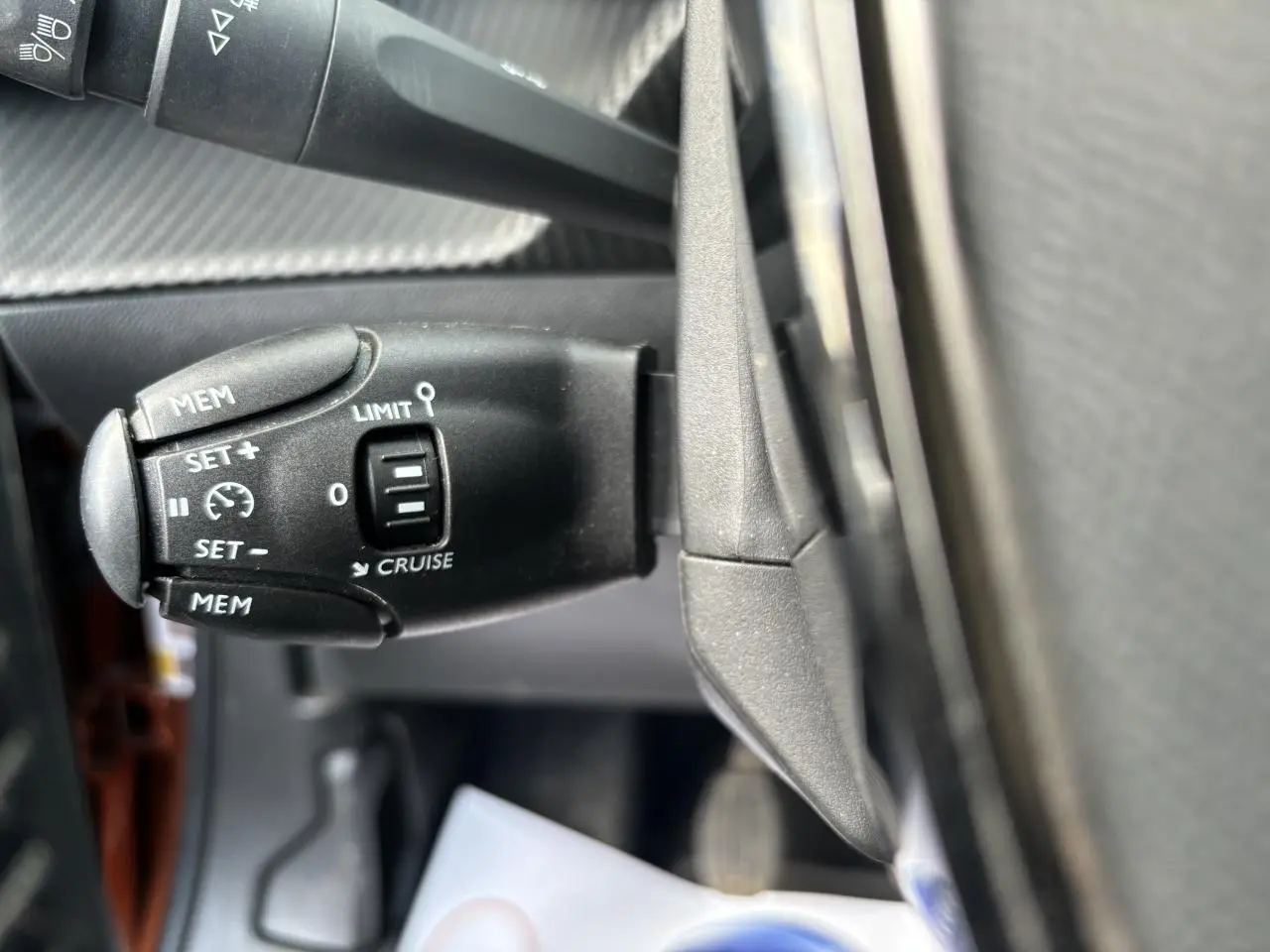 Gros plan sur la commande de régulateur de vitesse à gauche du volant dans un Peugeot 2008 Orange Fusion 2021.