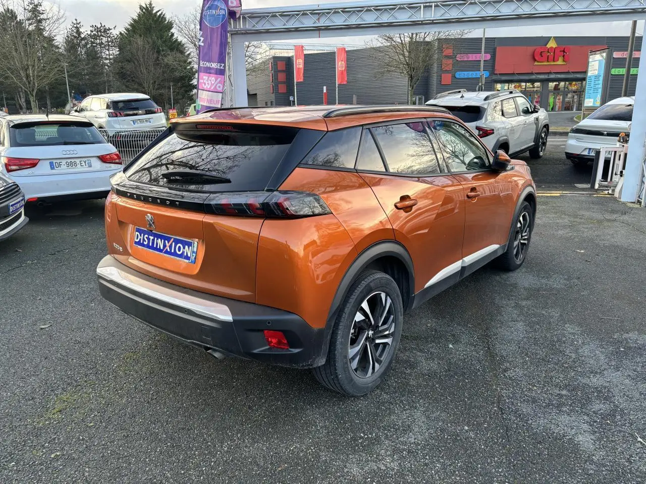 Vue 3/4 arrière droite d'un Peugeot 2008 orange fusion avec toit noir et feux arrière LED distinctifs.