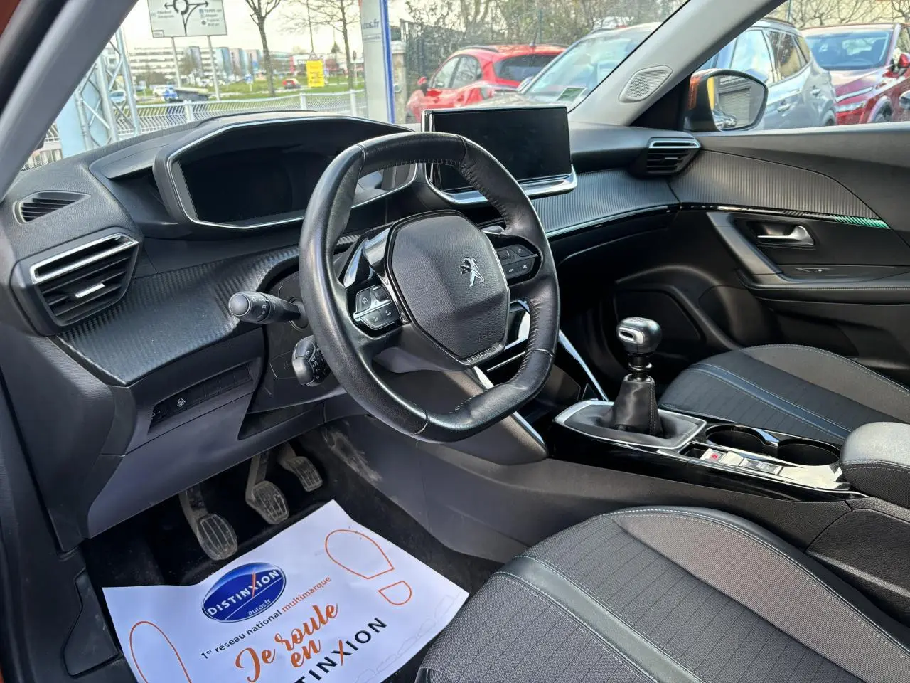 Intérieur avant droit du Peugeot 2008 2021 essence Orange Fusion, volant cuir compact et boîte manuelle visible.