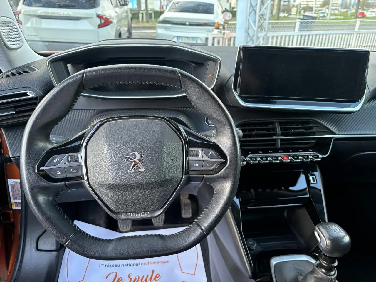 Vue intérieure centrée sur le volant cuir Peugeot et la console avec écran tactile du 2008 Orange Fusion 2021.