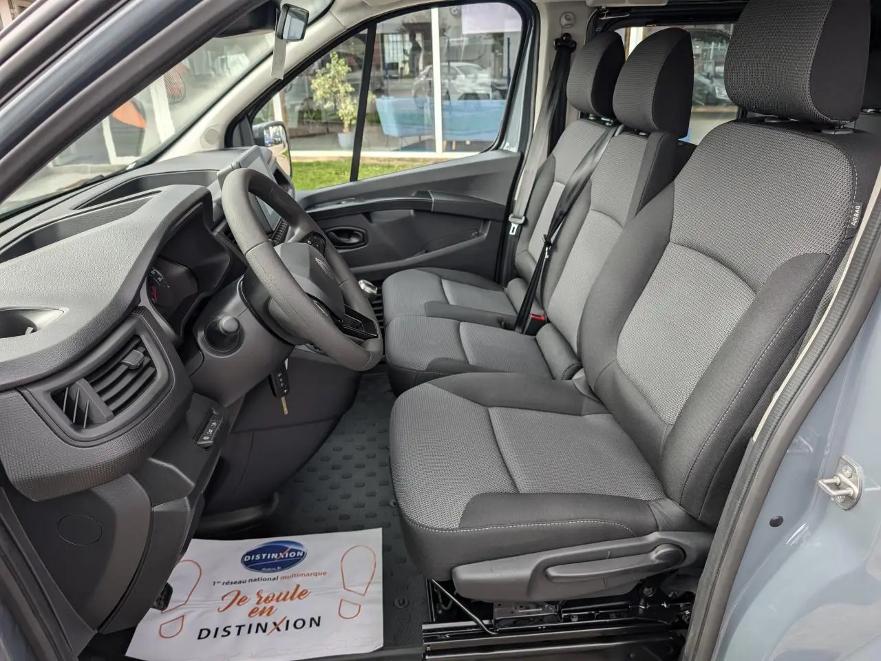 Intérieur côté conducteur du Renault Trafic Fourgon gris 2024, montrant la banquette tissu Kompo Black et le tableau de bord.