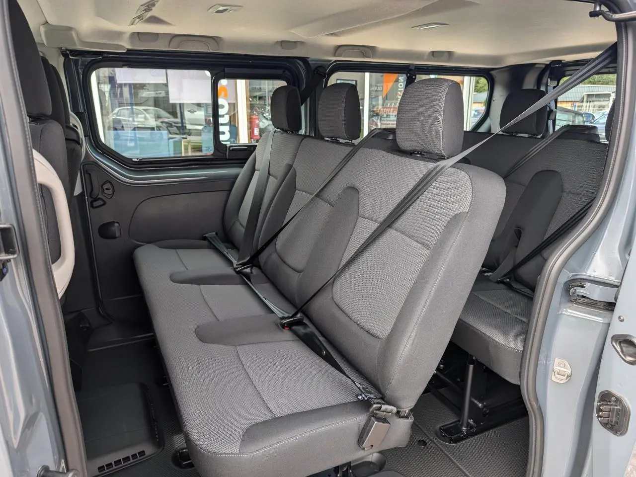Vue intérieure côté droit sur les sièges tissu gris Kompo Black du Renault Trafic Fourgon L2 2024 avec ceintures attachées.