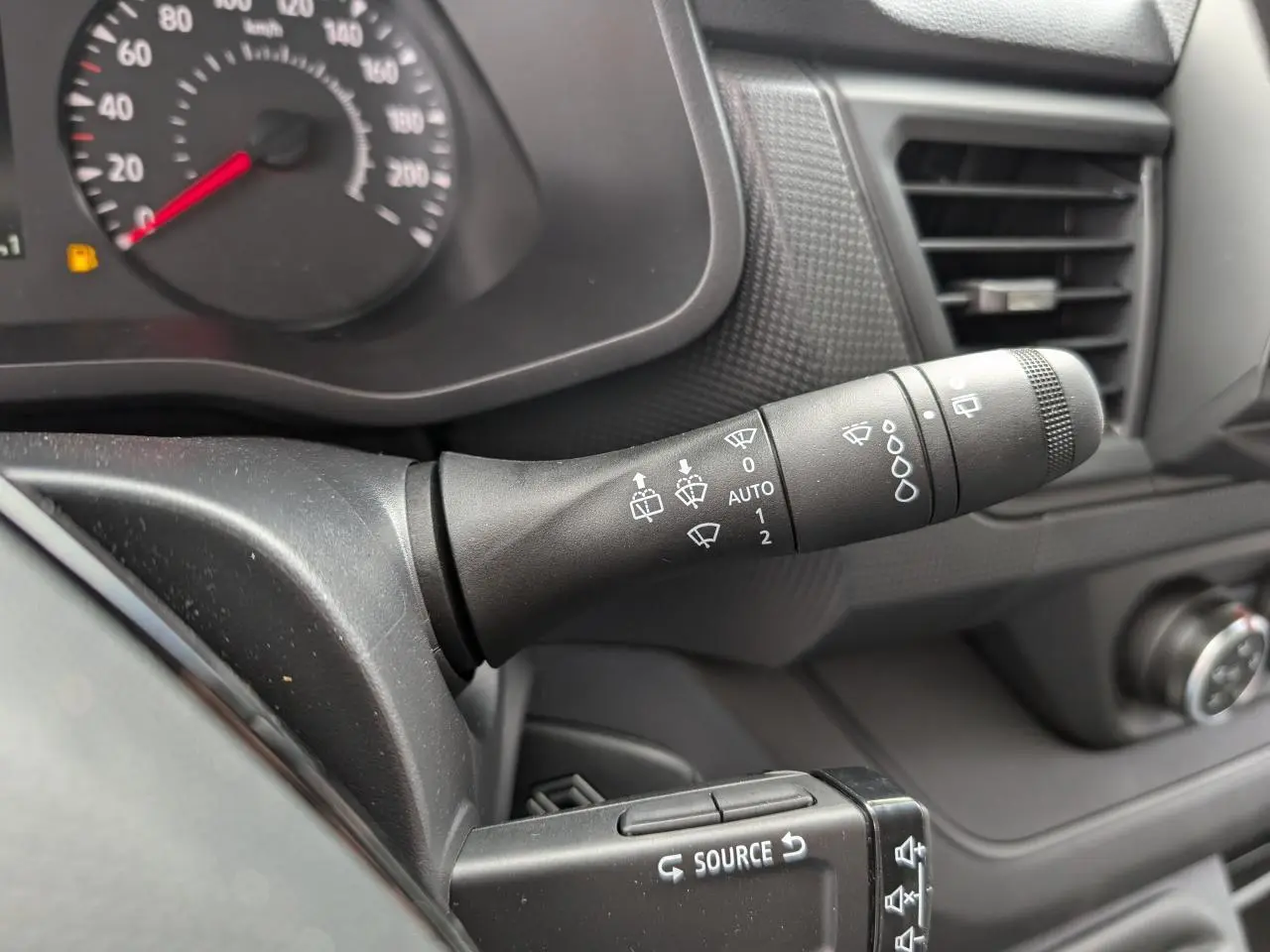Gros plan sur la commande d’essuie-glace à gauche du tableau de bord noir du Renault Trafic Fourgon gris 2024.