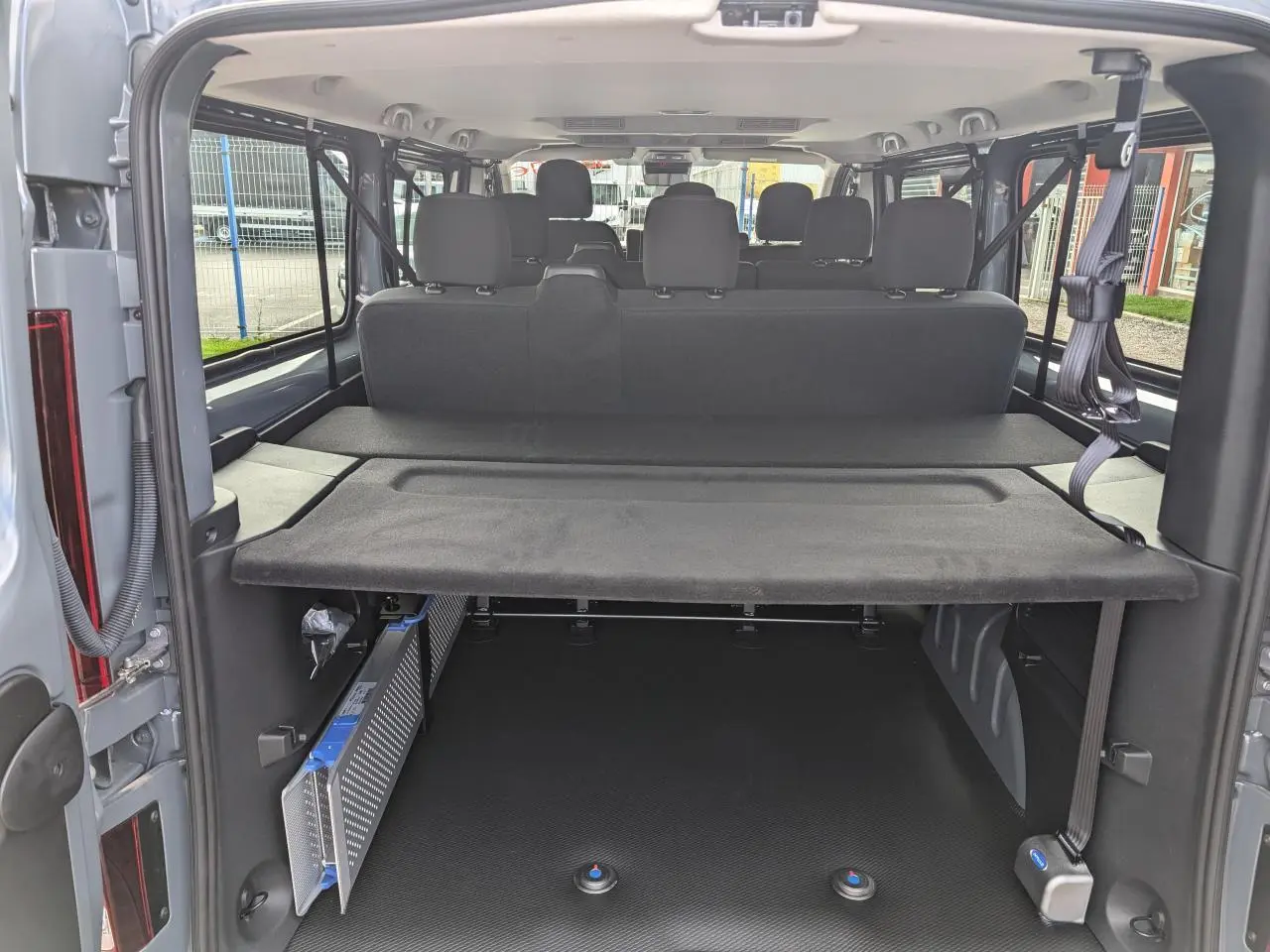 Vue arrière de l'intérieur du Renault Trafic Fourgon gris 2024 montrant la banquette et l'espace de chargement aménagé.