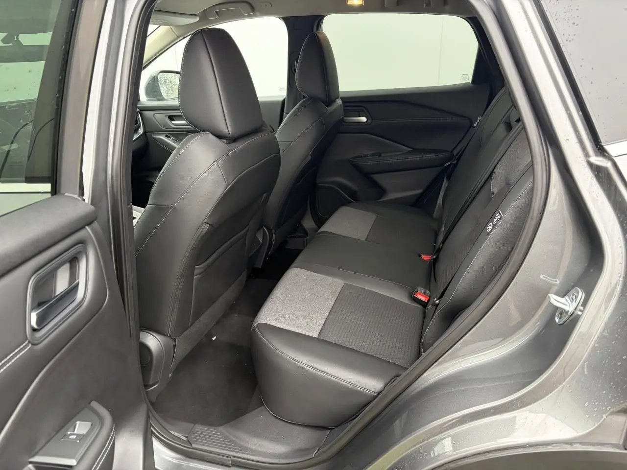 Vue côté droit sur l'intérieur arrière gris foncé du Nissan Qashqai 2025 avec sellerie mixte cuir et tissu.