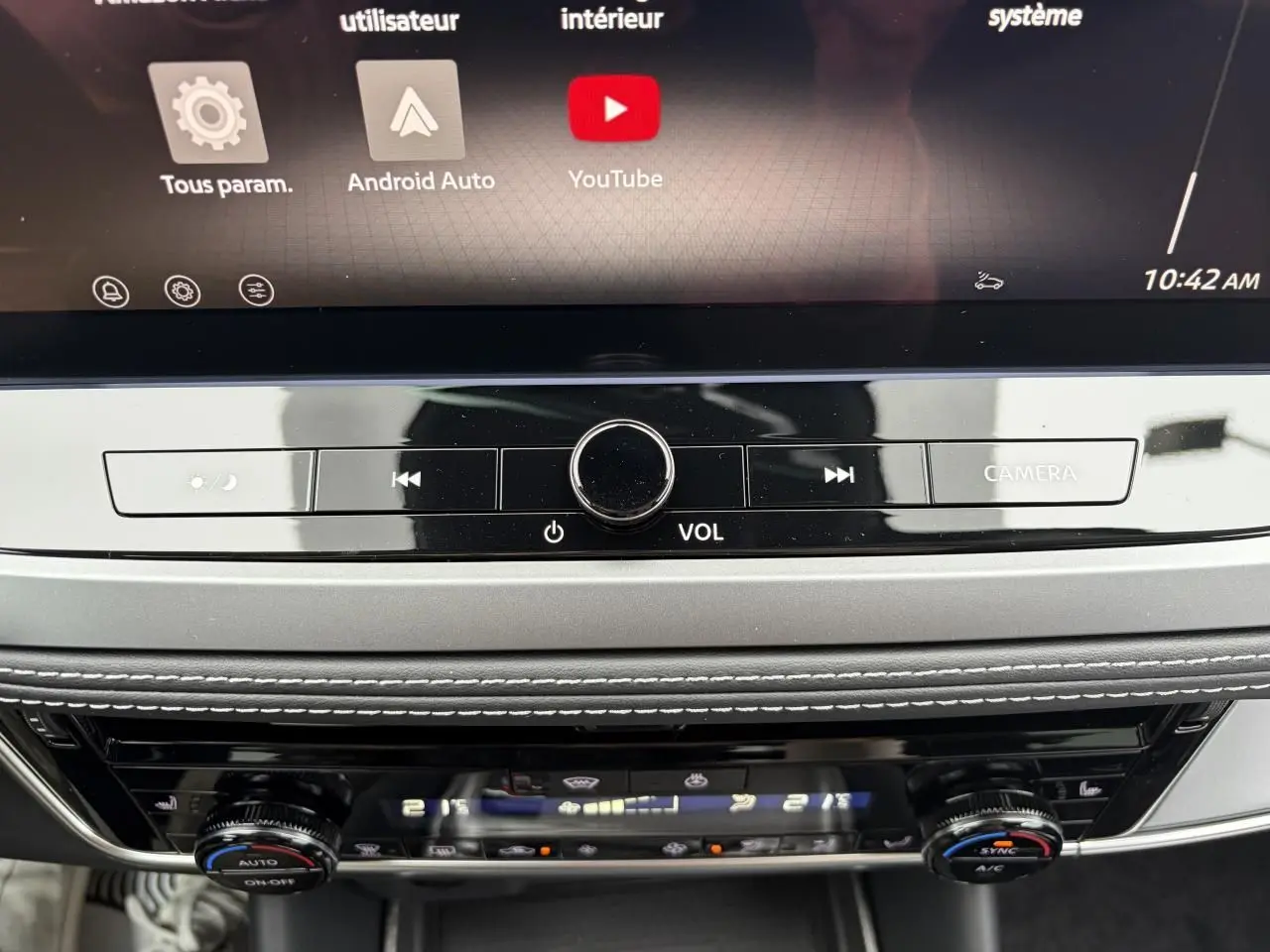Détail de la console centrale du Nissan Qashqai III 2025, avec commandes volume, climatisation bi-zone et écran tactile.