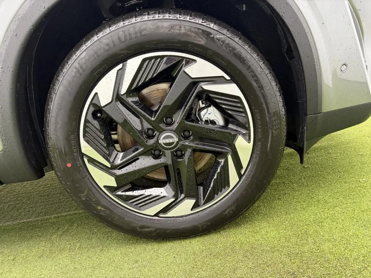 Gros plan sur la jante alliage 18 pouces bicolore noire et argentée du Nissan Qashqai III gris foncé, avec pneu Bridgestone.