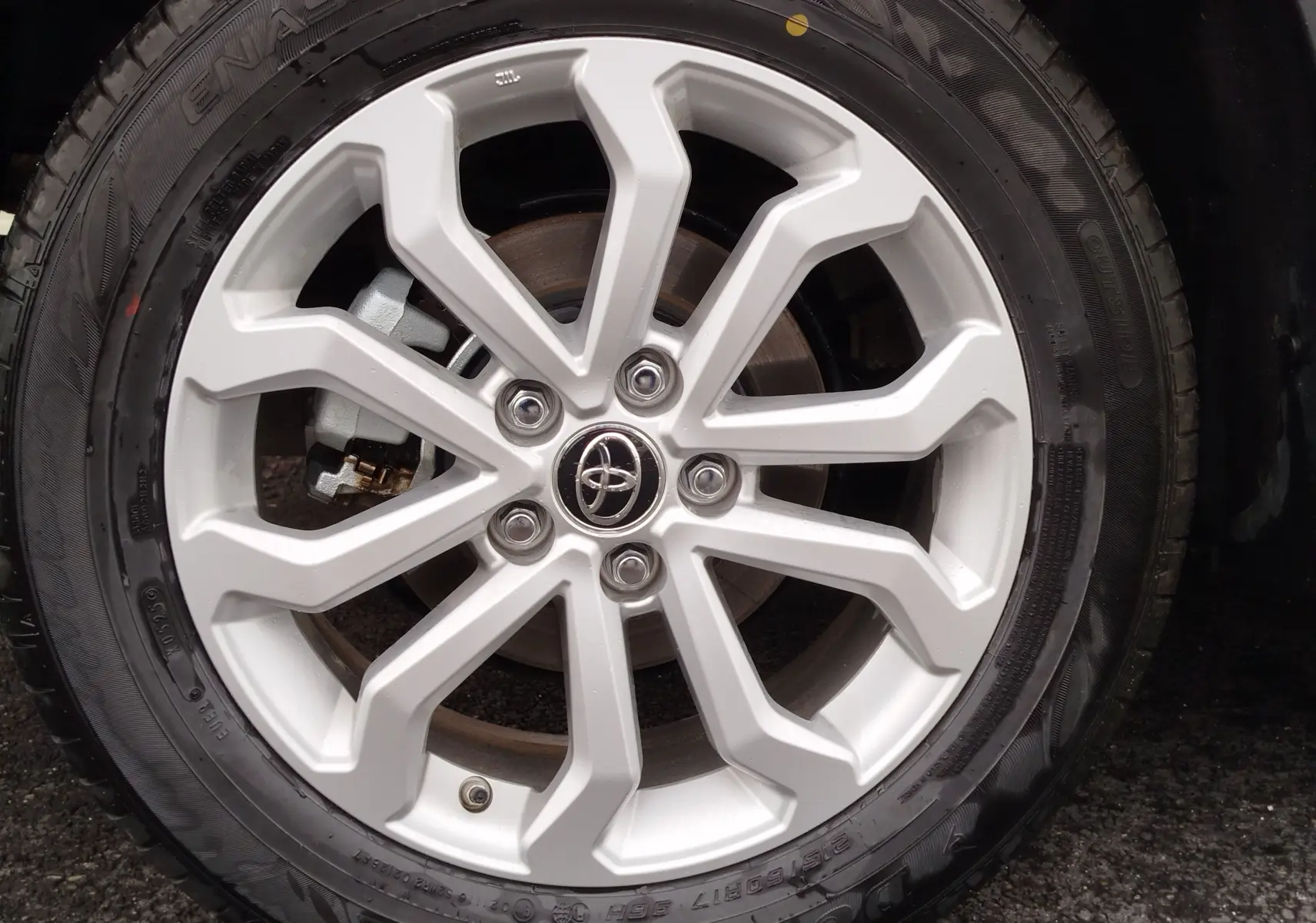 Gros plan sur la jante argentée au design moderne d'une Toyota Corolla Cross noire intense.