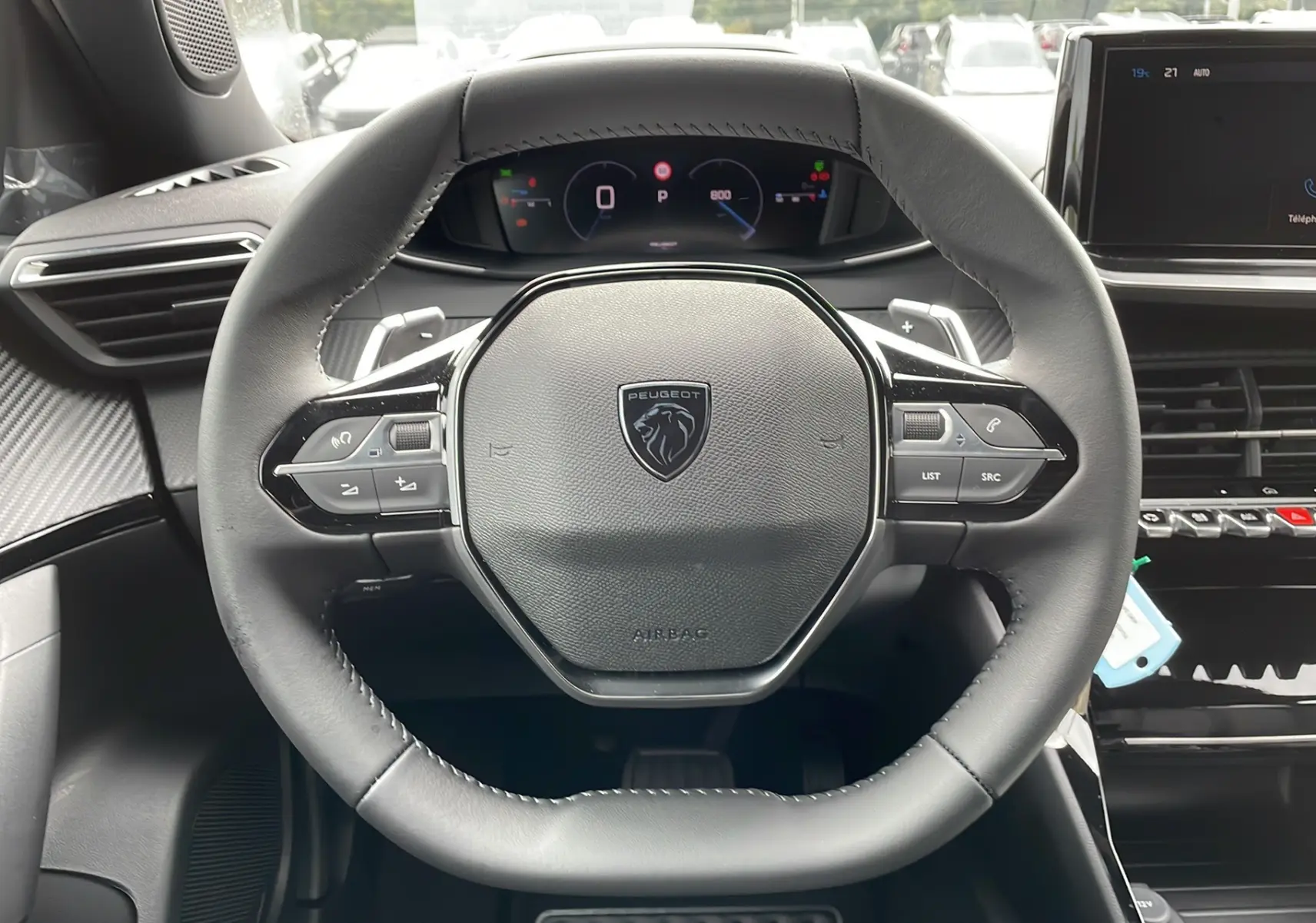 Vue rapprochée du volant cuir noir avec logo Peugeot, tableau de bord numérique et écran tactile du Peugeot 2008 2024.