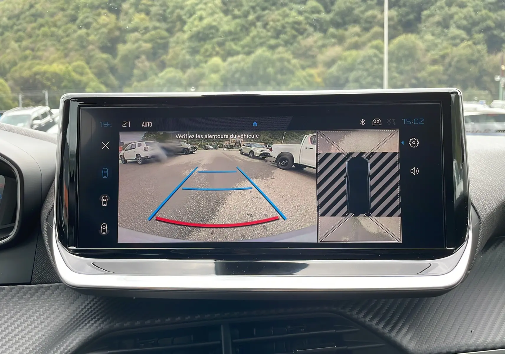 Écran central du Peugeot 2008 2024 montrant la caméra de recul avec vue arrière et top-down en stationnement.