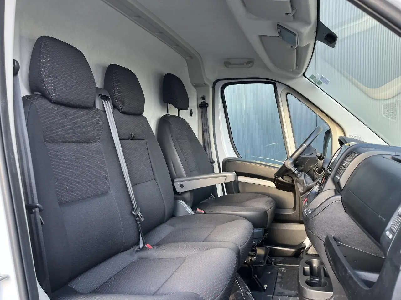 Vue intérieure côté gauche montrant les sièges avant noirs et la cabine spacieuse du fourgon Opel Movano 2024.