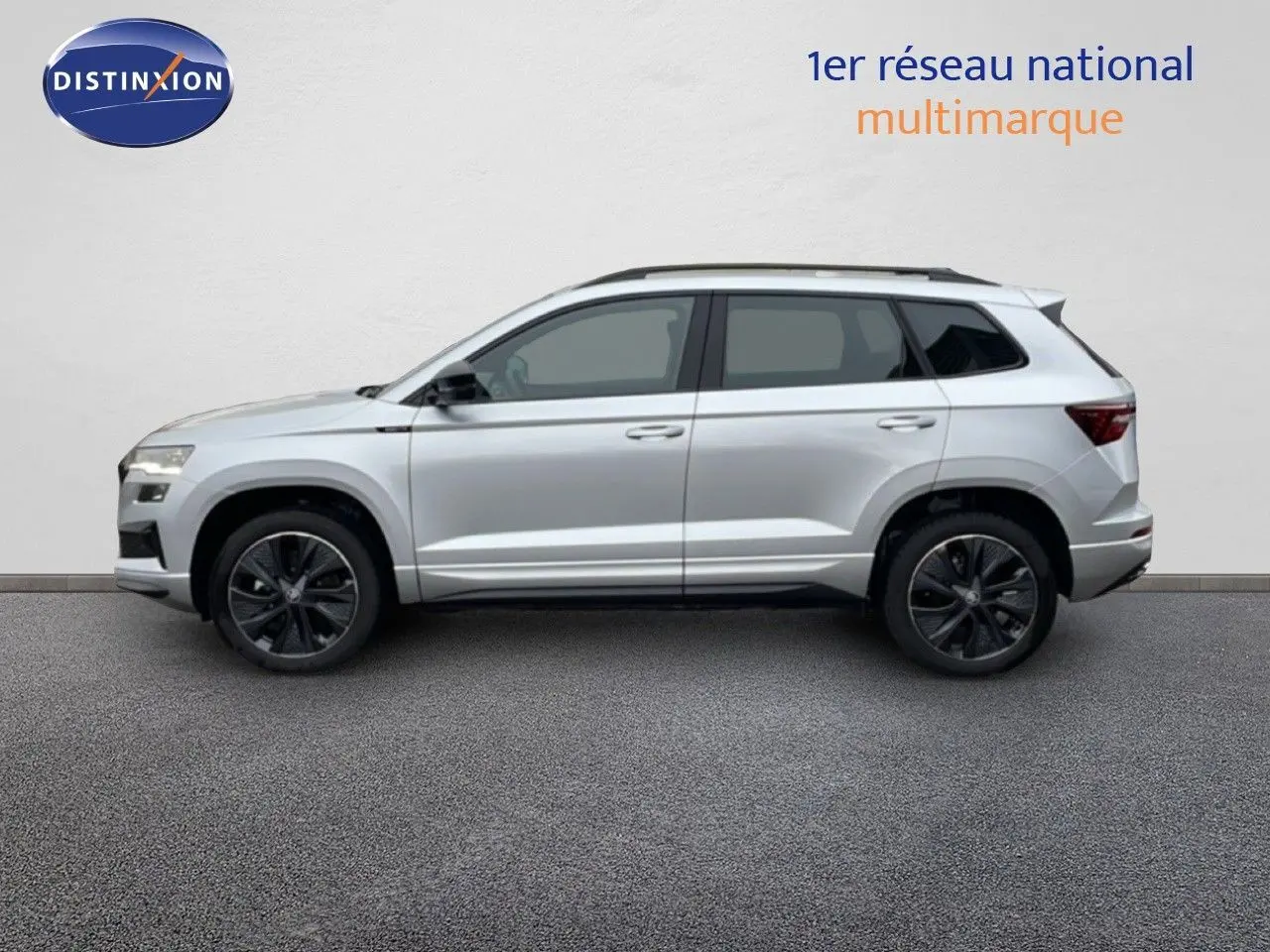 Vue latérale droite d'un SKODA KAROQ gris argent métallisé 2025 avec jantes noires bi-ton et toit noir.