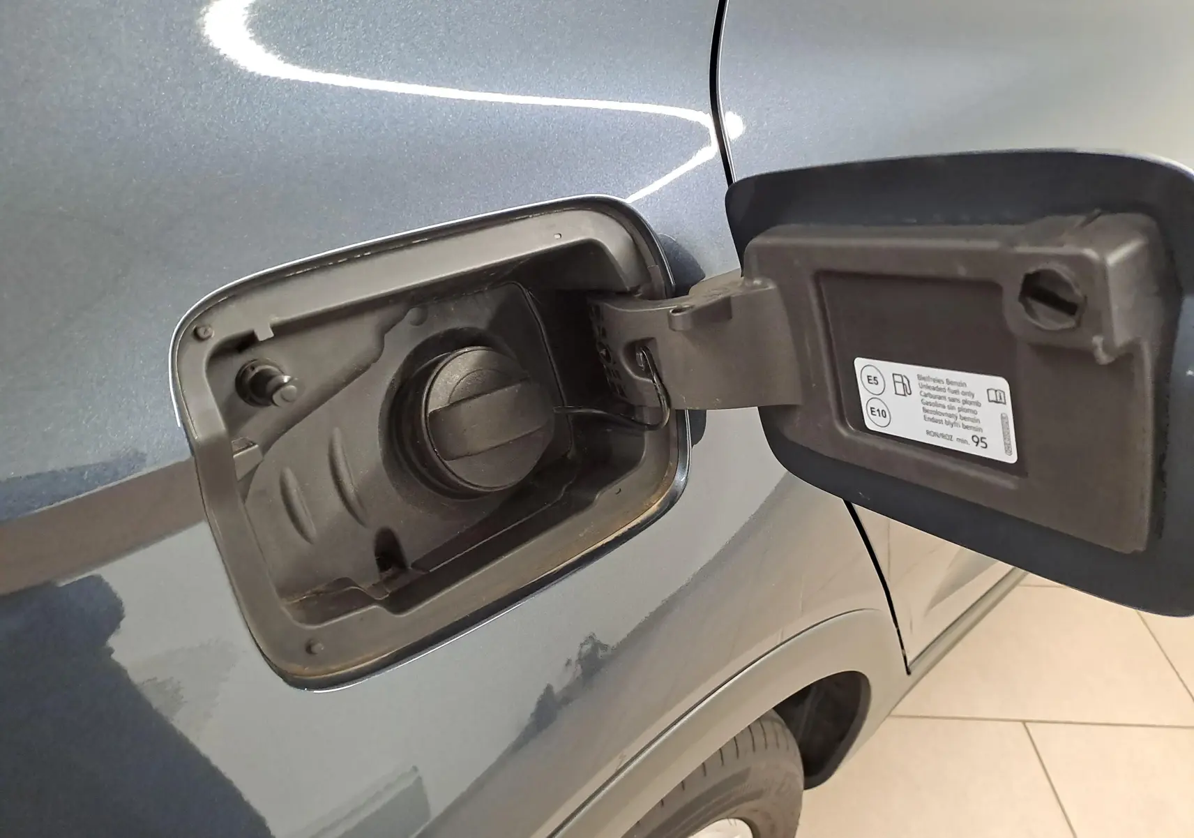 Gros plan sur la trappe à carburant ouverte du SEAT Arona gris magnétique, toit noir, côté gauche arrière.