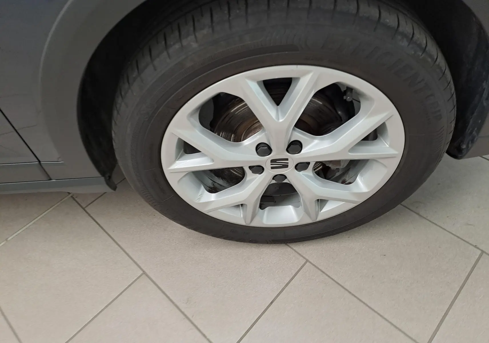 Gros plan sur la roue avant droite d'un SEAT Arona gris magnétique avec jante alliage argentée et logo central.