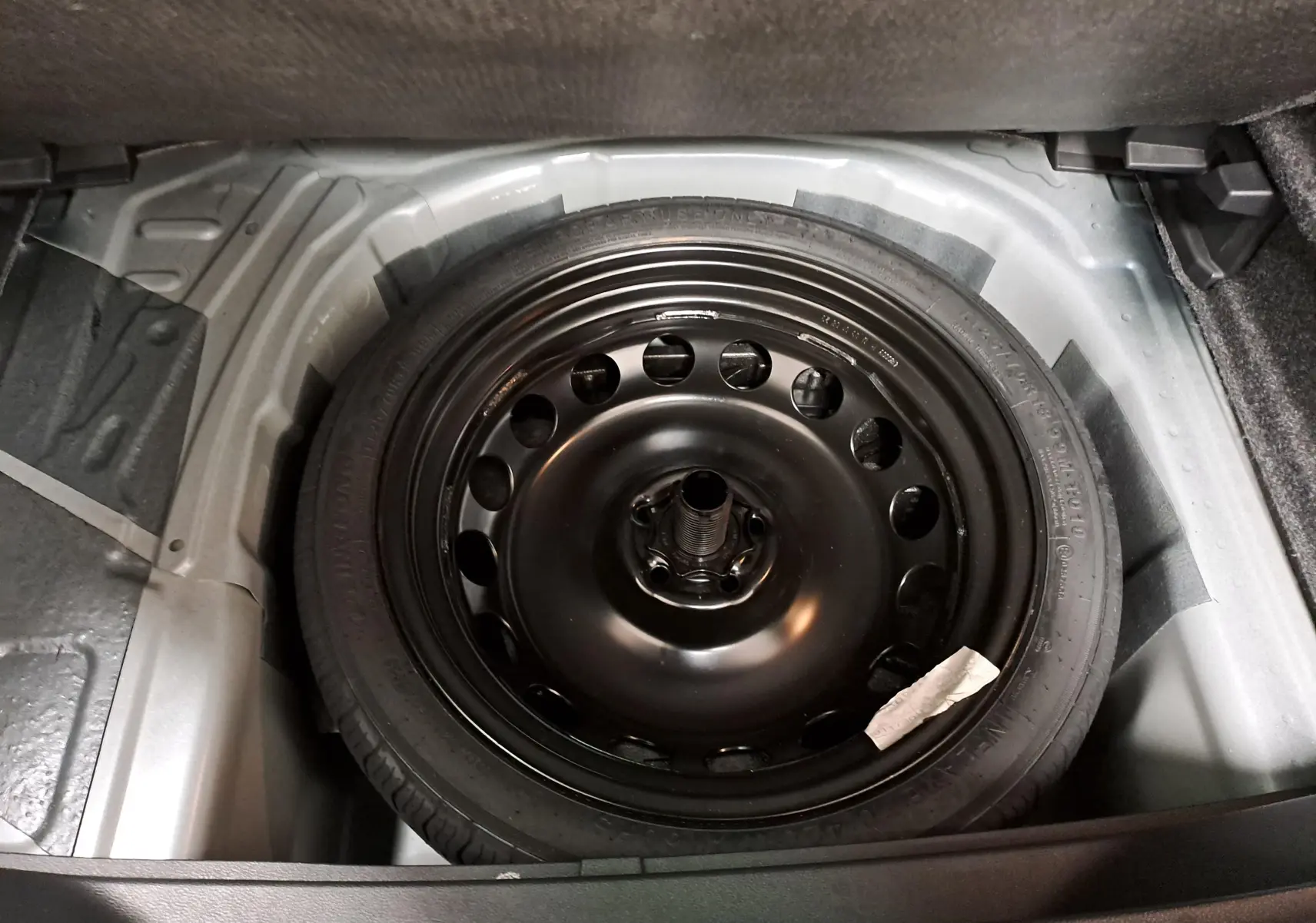 Gros plan sur la roue de secours compacte noire de 18 pouces dans le coffre du SEAT Arona 2024.