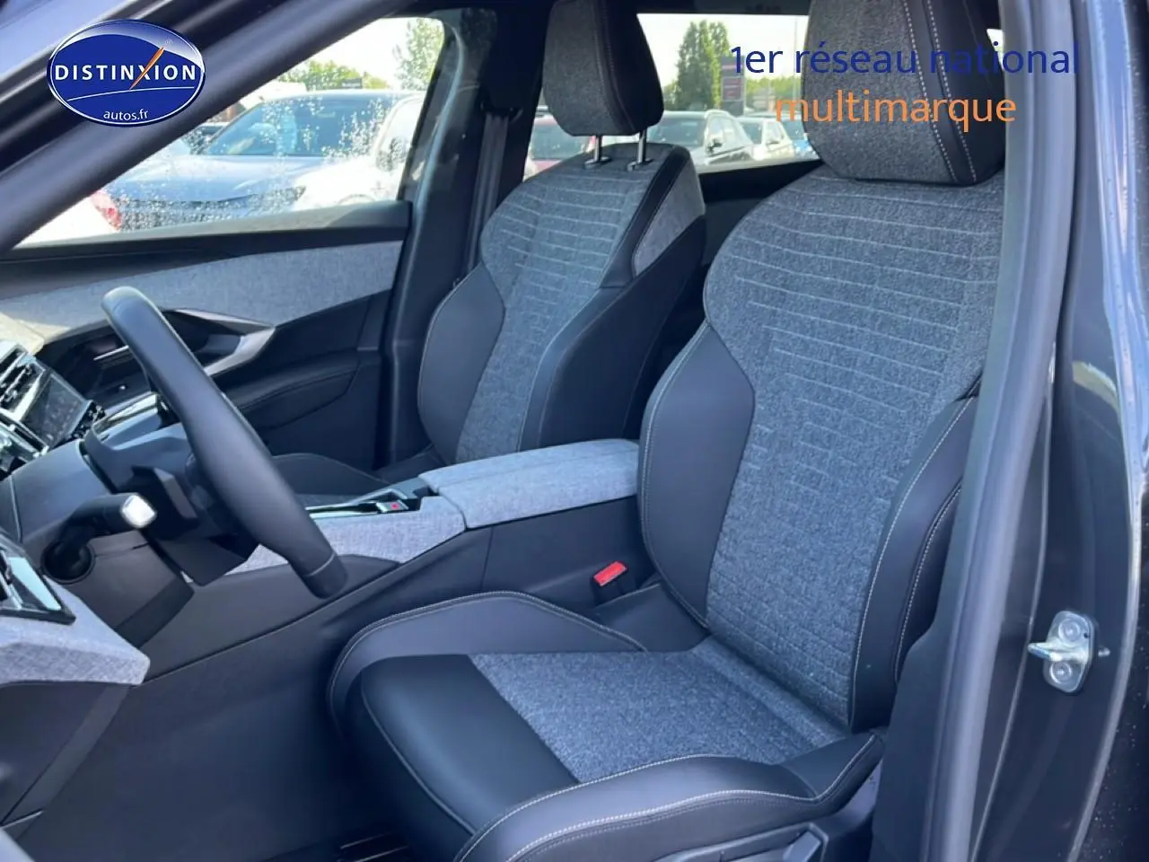 Vue intérieure côté conducteur du Peugeot 5008 gris titane, sièges tissu et cuir avec accoudoir central.