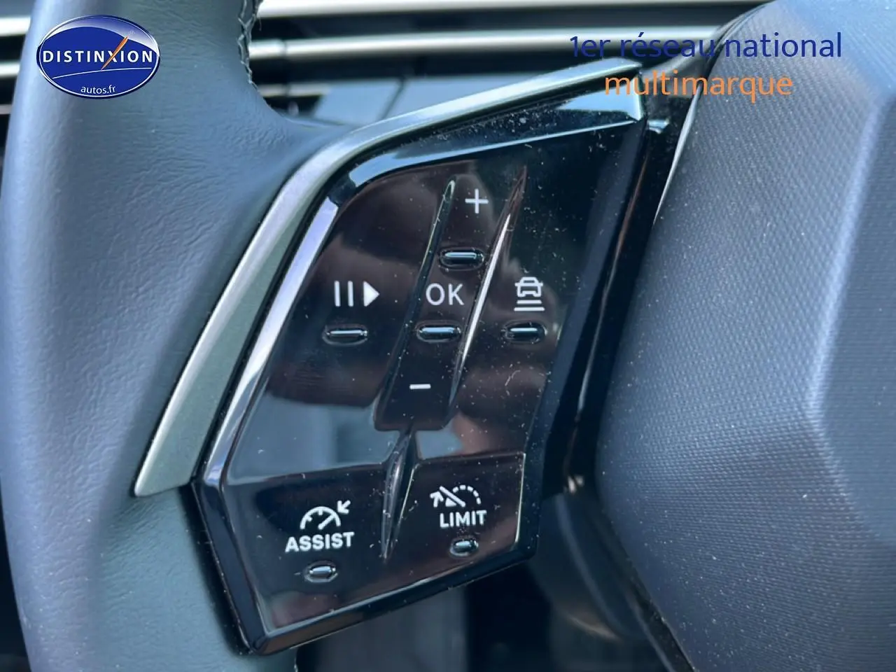 Gros plan sur les commandes au volant noir du Peugeot 5008 Hybrid 145 allure e-dcs6, avec boutons multifonctions visibles.